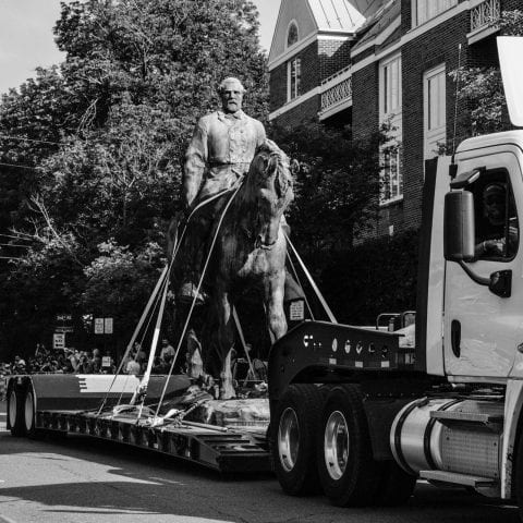 A statue of Robert E. Lee is carried away on a flatbed truck